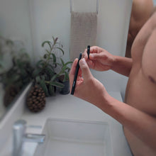 Load image into Gallery viewer, Stealth Fighter Concealer Pen for Men prepared to be used by hands in bathroom mirror
